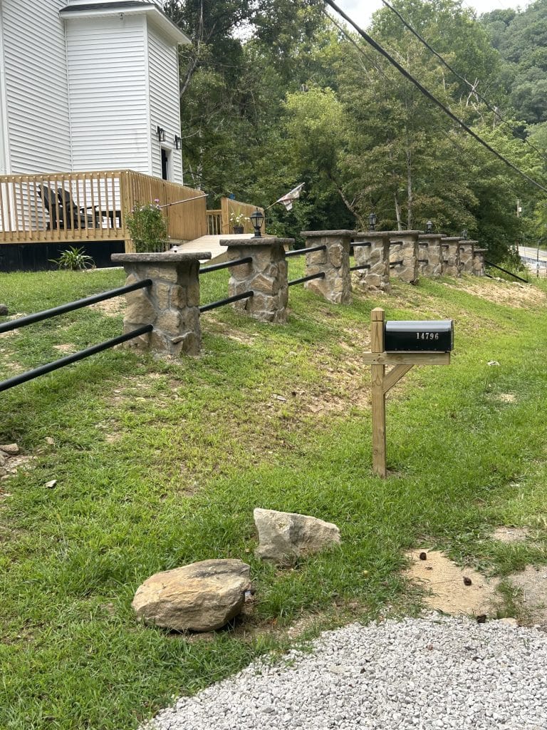 Seventeen stone piers connected by rails forming a boundary along the lodge grounds.