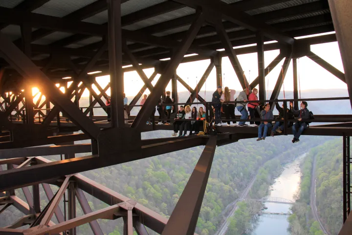 “Visitors on the New River Gorge Bridge Walk tour walking along the catwalk beneath the bridge in Fayetteville, West Virginia.”
